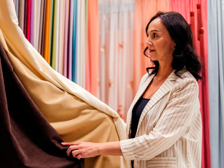Een vrouw die naar een selectie gordijnen in diverse kleuren kijkt