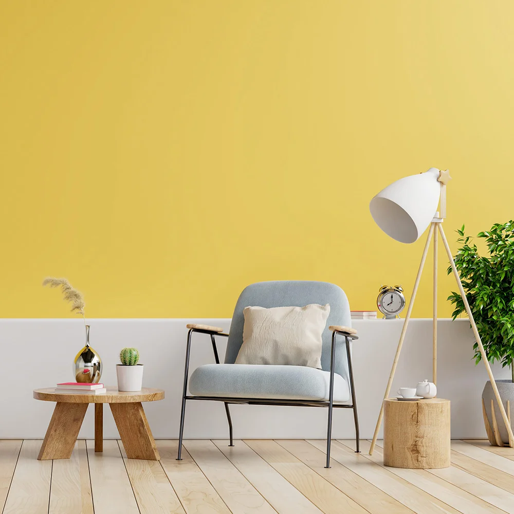 Afbeelding met lichtblauwe stoel, vloerlamp, houten bijzettafeltjes en een gele muur op de achtergrond.