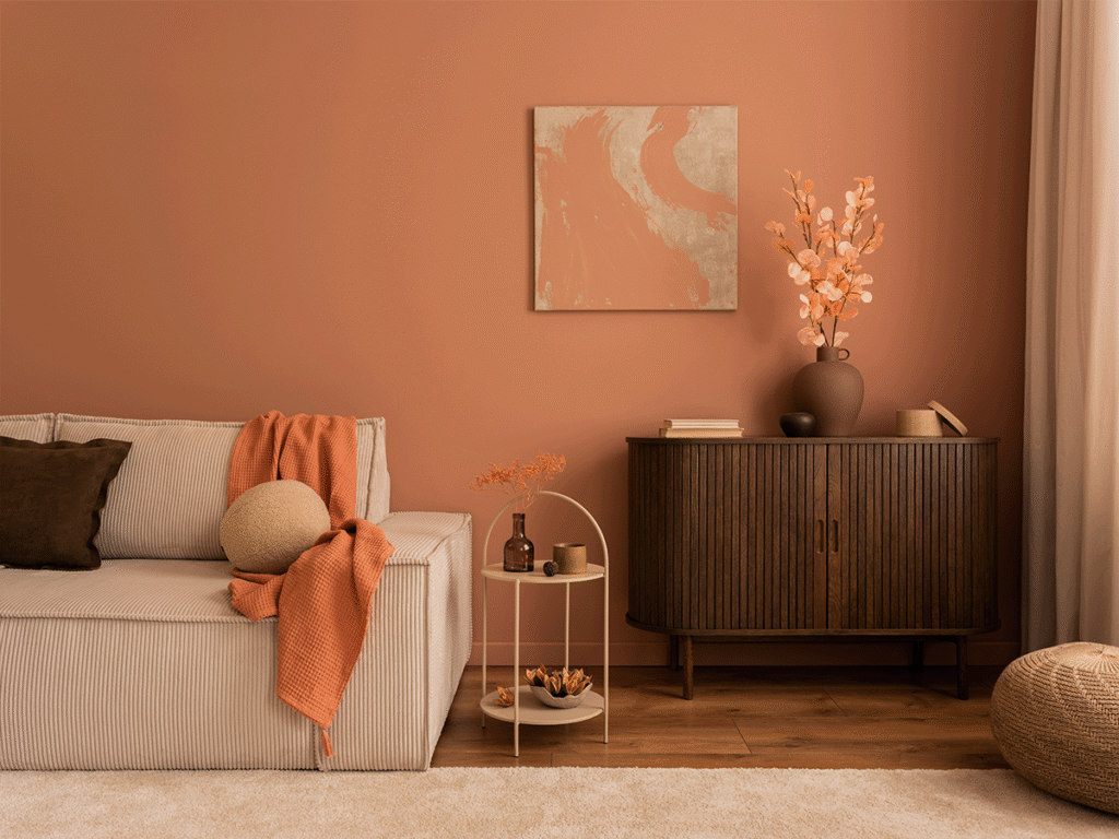 Modern interieur met een terracotta muur, een beige bank, een houten dressoir en warme decoraties in aardetinten.